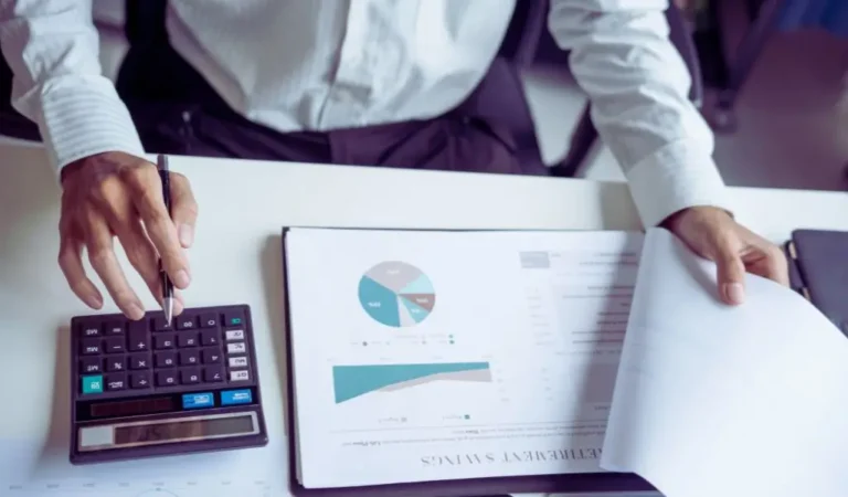 Mężczyzna analizuje dokumenty finansowe i korzysta z kalkulatora – obniżenie kosztów w firmie przez zatrudnienie osób niepełnosprawnych