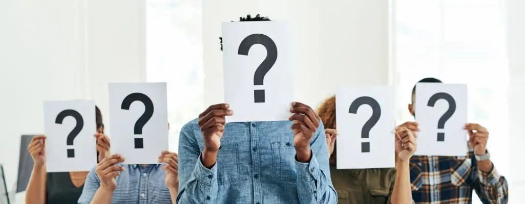 Zdjęcie w artykule - gdzie szukać pracy zdalnej. Na obrazku sylwetki osób zakrywających swoje twarze kartkami, na których widnieje znak zapytania.