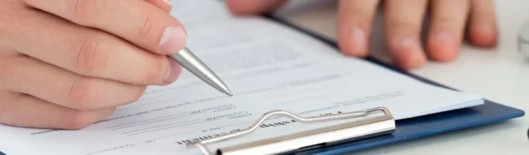 Jak złożyć wniosek o dofinansowanie wynagrodzeń do PFRON? Instrukcja krok po kroku 7 Zdjęcie w artykule PFRON wniosek o dofinansowanie wynagrodzeń. Widoczny fragment dłoni wypisującej długopisem druk wniosku.