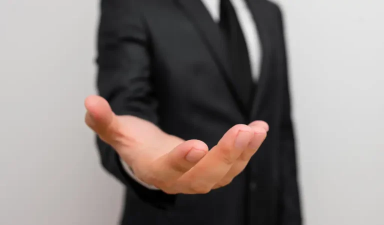 Obrazek wyróżniający w artykule - uprawnienia pracownika z orzeczeniem. Bez zdjęciu w pierwszym planie wyciągnięta otwarta dłoń, na drugim planie sylwetka mężczyzny. Zdjęcie sugeruje otwartość na realizację uprawnień pracownika.