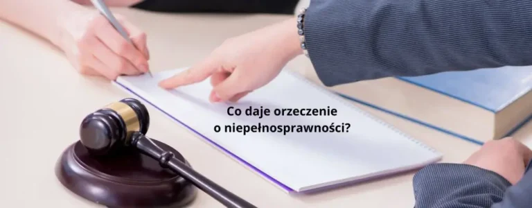 Obrazek wyróżniający do artykułu - co daje orzeczenie o niepełnosprawności. Na obrazku widzimy scenę przedstawiającą podpisywanie dokumentów. Na pierwszym planie znajduje się drewniany młotek sędziowski na podstawce, sugerujący kontekst prawny lub sądowy. Na stole leży otwarty notatnik lub dokument, na którym osoba po lewej stronie coś pisze. Druga osoba, widoczna po prawej stronie, wskazuje na dokument palcem. Na dokumencie umieszczony jest tekst: "Co daje orzeczenie o niepełnosprawności?". Obrazek przedstawia kontekst formalnego procesu, który może być związany z uzyskaniem orzeczenia o niepełnosprawności.