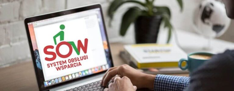 Obrazek wyróżniający do artykułu - sow pfron. Na zdjęciu widać osobę siedzącą przed laptopem, na ekranie którego wyświetlona jest strona internetowa z logiem "SOW" oraz napisem "System Obsługi Wsparcia". Logo składa się z dużych, kolorowych liter: S, O z sylwetką osoby na wózku inwalidzkim i W. Pod logiem znajduje się pełna nazwa systemu. Osoba korzystająca z laptopa i trzyma ręce na klawiaturze, pisząc lub nawigując po stronie. W tle znajduje się roślina doniczkowa na biurku oraz książki, co sugeruje, że jest to spokojne i uporządkowane miejsce w domu.