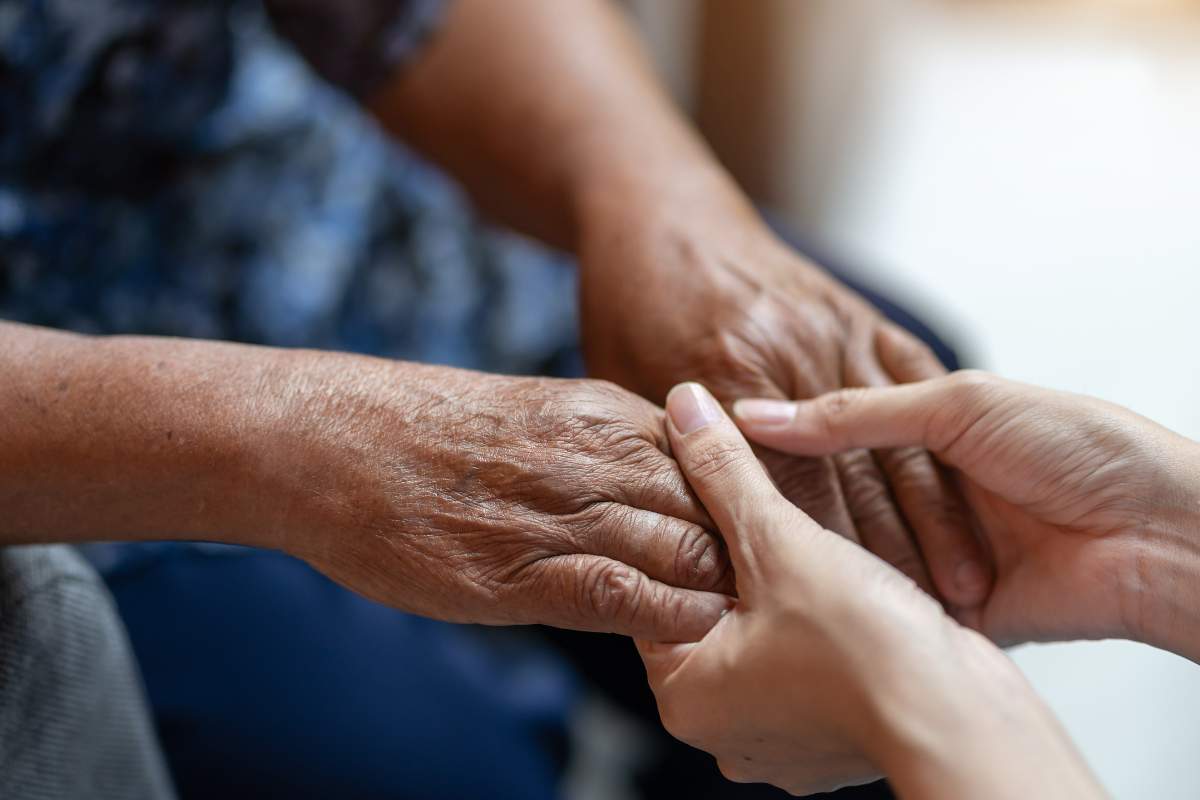 Cus Żyrardów na zdjęciu dłonie starszej osoby dotykane przez dłonie młodszej