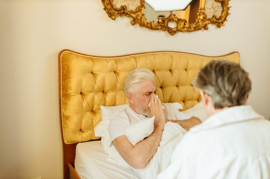 opieka nad osoba starszą , na zdjęciu mężczyzna leżący w łóżku i osoba opiekującą się nim