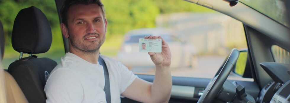 na zdjęciu kierowca pokazujący prawo jazdy, prawdopodobnie z kodem 95