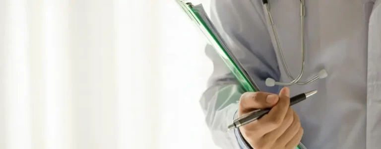 Obrazek wyróżniający do artykułu - lekki stopień niepełnosprawności. Widoczny fragment torsu lekarza, który trzyma dokumenty oraz długopis w ręce. Z ramienia zwisa mu stetoskop.