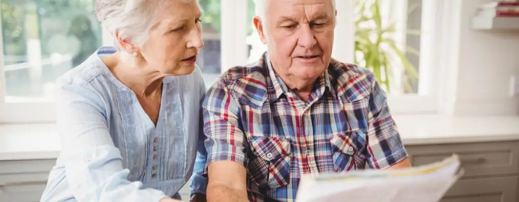 Zdjęcie w artykule - ile wynosi dodatek pielęgnacyjny. Starszy mężczyzna i kobieta z zaciekawieniem przeglądają dokumenty.