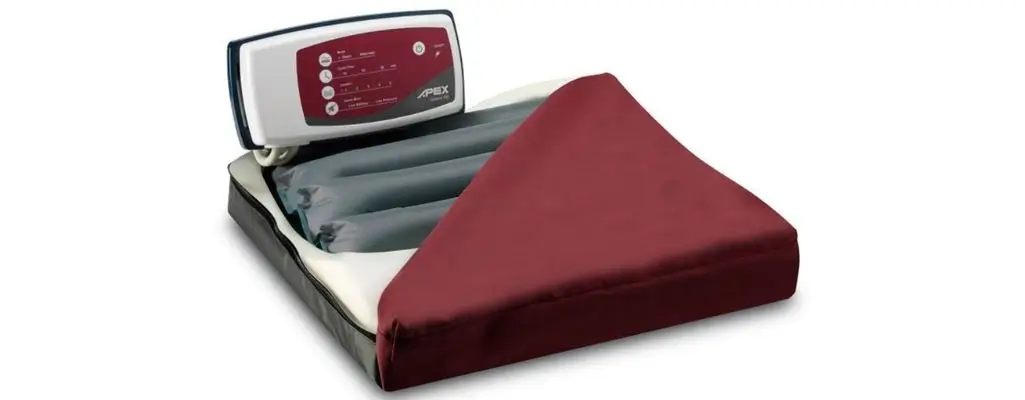 Zdjęcie w artykule - poduszka przeciwodleżynowa. Przedstawia model poduszki zmiennociśnieniowej w czerwonym pokrowcu wraz z leżącą obok pompą.