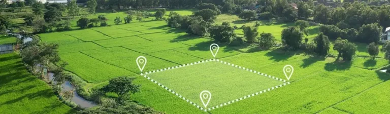 Obrazek wyróżniający do artykułu - konwersja jednostek. Przedstawia z góry pole podzielone na kwadratowe działki, z zaznaczonym obszarem ograniczonym białą przerywaną linią i czterema ikonami lokalizacji. Jest to typowy widok dla ilustracji wykorzystywanych w geodezji lub planowaniu przestrzennym, sugerujący pomiary powierzchni gruntu.