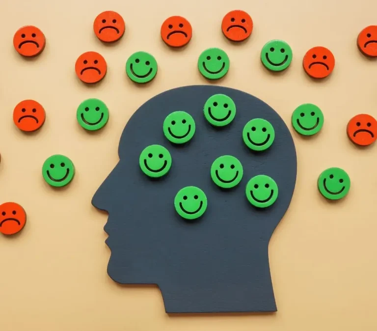 Obrazek wyróżniający do artykułu - negatywne cechy charakteru. Przedstawiona jest ilustracja głowy w profilu na pomarańczowym tle. Głowa jest wypełniona zielonymi uśmiechniętymi buźkami, ale wokół niej umieszczone są czerwone, smutne buźki. Obraz może symbolizować wewnętrzny kontrast między pozytywnymi a negatywnymi cechami lub doświadczeniami, wskazując na zmagania wewnętrzne lub wahania nastroju.