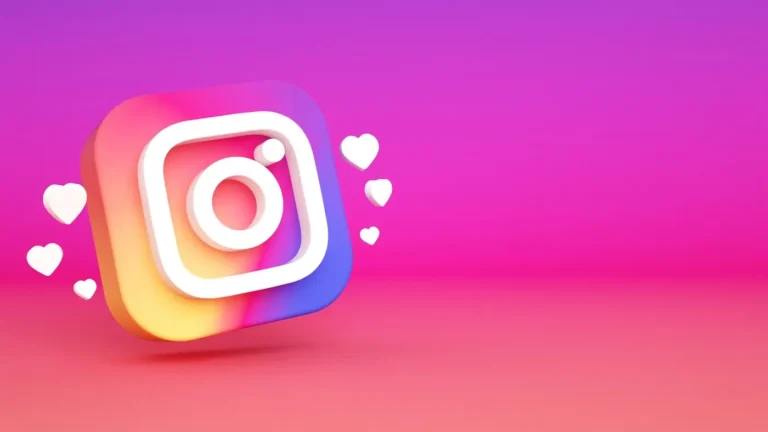 Na obrazku widoczna jest trójwymiarowa ikona aplikacji Instagram, która unosi się nad gradientowym tłem. Tło przechodzi od koloru różowego u góry do pomarańczowego u dołu. Ikona Instagrama jest kolorowa, z charakterystycznym przejściem barw od różu, przez pomarańcz, do niebieskiego. Obok ikony znajdują się unoszące się białe serduszka, które symbolizują polubienia. Całość tworzy nowoczesny i przyciągający wzrok wizerunek związany z mediami społecznościowymi.