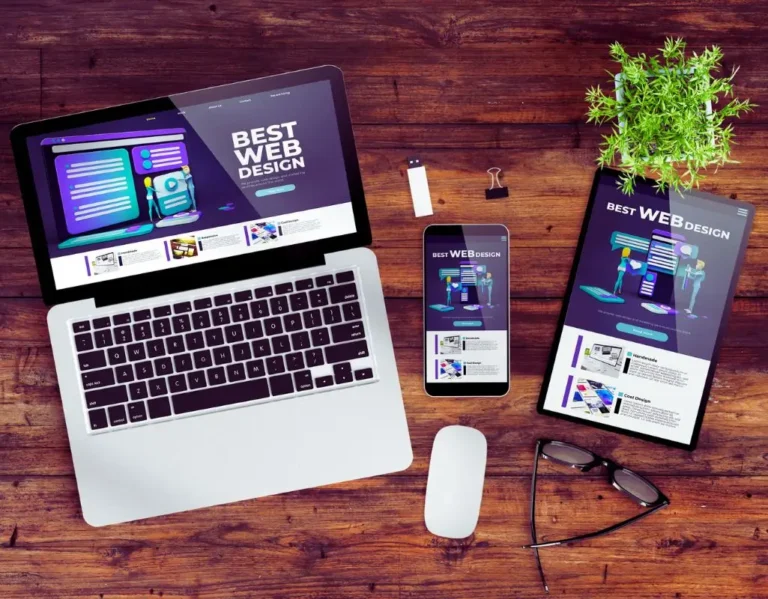 obrazek do artykułu - jak zostać ux designerem? Obraz przedstawia zestaw urządzeń elektronicznych – laptop, smartfon i tablet – wyświetlających stronę internetową z hasłem "Best Web Design". Na drewnianym stole znajdują się również okulary, mysz komputerowa, pendrive, spinacz oraz roślina w doniczce. Wygląd strony na wszystkich urządzeniach wskazuje na responsywny design, który dopasowuje się do różnych ekranów.