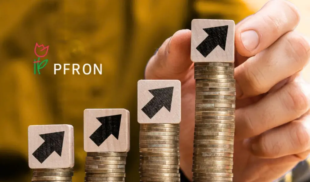 Czy wyższe wpłaty PFRON od czerwca 2025 dotyczą także Ciebie? 1 Cztery rosnące stosy monet z klockami ze strzałkami w górę, symbolizujące wyższe wpłaty PFRON od przedsiębiorców, z ręką sięgającą po najwyższy stos i logo PFRON w tle. Obraz oddaje poczucie wzrostu kosztów i zobowiązań finansowych.